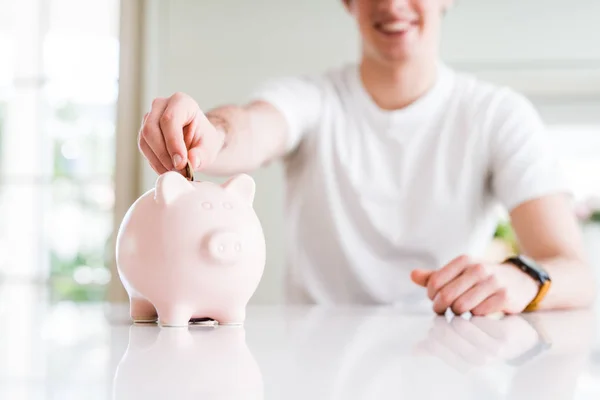 Primer plano del hombre poniendo una moneda dentro de la alcancía como ahorro o en — Foto de Stock