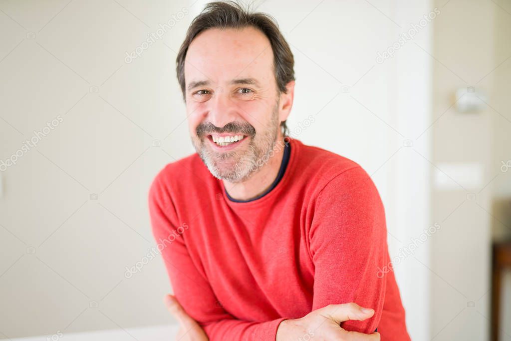 Handsome middle age man smiling looking at the camera at home