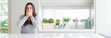 Güzel genç kadın evde beyaz masaya oturan geniş açı resim kaplama ağız elle hata için şok. Gizli kavramı.