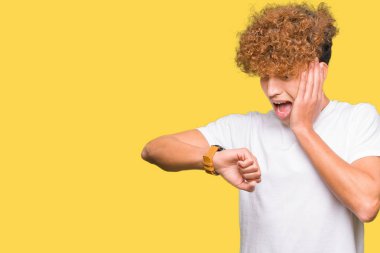 Casual beyaz t-shirt arıyorsunuz seyretmek zaman endişeli, geç korkuyor giyen afro saçlı Genç yakışıklı adam