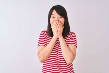 Genç güzel Çinli kadın izole beyaz arka plan üzerinde kırmızı çizgili t-shirt giyen gülme ve elleri, dedikodu ve skandal kavramı ile ağız kapsayan kıkırdama utandım