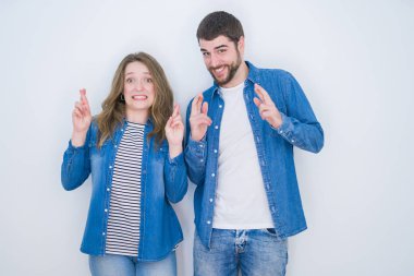 Beyaz izole arka plan üzerinde birlikte ayakta genç güzel çift umut ve gözler ile gülümseyen geçti parmak kapalı. Şans ve batıl fikir.