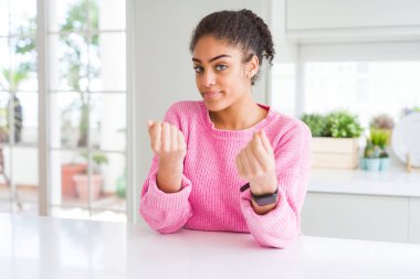 Afro saç ile güzel Afrikalı Amerikan kadın rahat pembe kazak eller ile para jest yapıyor giyen, maaş ödeme için soran, milyoner iş