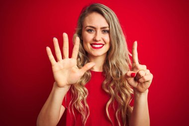 Kırmızı izole arka planda duran temel t-shirt ayakta giyen genç güzel kadın ve emin ve mutlu gülümseyen sırasında parmak numarası altı ile işaret.
