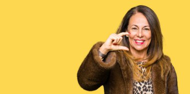 Vizon ceket gülümseyen ve süre seyir ve kamera boyutu işaret parmaklarıyla yapıyor el ile kendine güvenen el hareketi giyen güzel orta yaş zarif kadın. Ölçü kavramı.