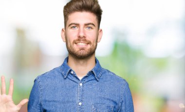 Genç yakışıklı sarışın adam gösterilen ve parmakları ile işaret rahat kot gömlek giymiş beş kendinden emin ve mutlu gülümseyerek iken numara.