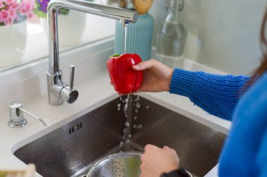 Genç kadın lavabo su kullanarak sebze ve meyve yıkama