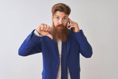 Kızgın yüz ile izole beyaz arka plan üzerinde Smartphone konuşurken genç Redhead İrlandalı işadamı, aşağı başparmak ile nefret gösteren negatif işareti, ret kavramı
