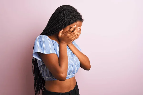 身穿条纹T恤的非洲裔美国妇女站在孤立的粉色背景上 脸上挂着忧郁的表情 一边哭一边用手捂住脸 抑郁症的概念 — 图库照片