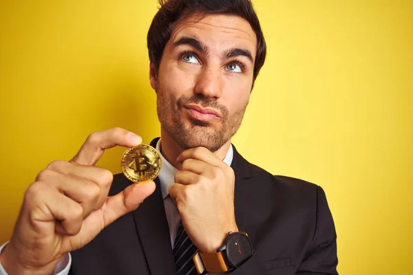 Young Handsome Businessman Holding Bitcoin Standing Isolated Yellow Background Serious — Stock Photo, Image