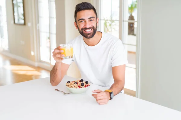 Hombre guapo sonriendo comiendo desayuno saludable y bebiendo orang —  Fotos de Stock