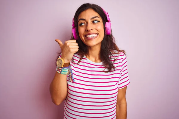 분홍색 배경을 헤드폰을 사용하여 음악을 아름다운 여성은 행복한 얼굴을 손가락으로 — 스톡 사진