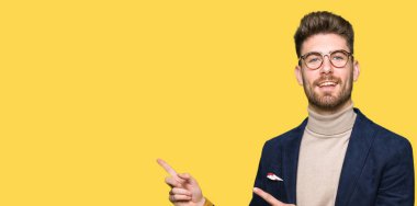 Gülümseyen ve iki elleri ve parmakları ile tarafına işaret kamera bakarak gözlüklü genç yakışıklı iş adamı.