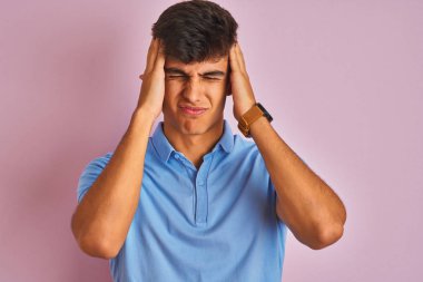 Mavi polo giyen genç hintli adam izole pembe arka plan üzerinde ayakta baş ağrısı umutsuz muzdarip ve stresli çünkü ağrı ve migren. Eller baş üstünde.
