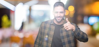 Yakışıklı delikanlı hareketi el ile mutlu yaşasın yapıyor izole arka plan üzerinde. Kameraya bakarak başarı gösteren ile ifade onaylama.