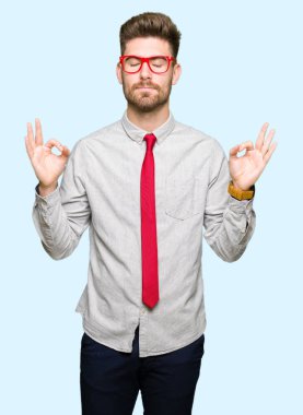 Genç yakışıklı iş adam gözlük rahatla ve gülümseyen gözlerle kapalı parmak jestle meditasyon yapıyor. Yoga kavramı.