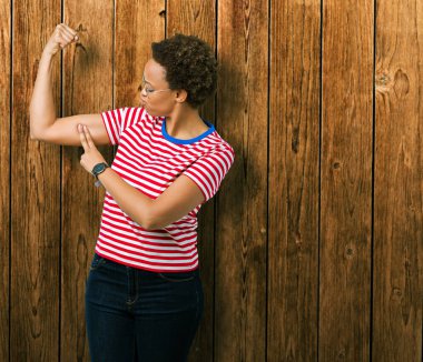 Güzel genç Afro-Amerikan kadın kol kas, kendinden emin ve güç gurur gösteren izole arka plan güçlü kişi üzerinde gözlük