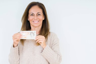 Orta yaş kadın tutan 10 kilo banka notu izole arka plan üzerinde mutlu bir yüz ayakta ve gülümseyen emin bir gülümseme ile diş gösteren