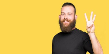 Gösterilen ve parmakları ile işaret rahat t-shirt giyen genç sarışın adam kendinden emin ve mutlu gülümseyerek iken üçüncü.