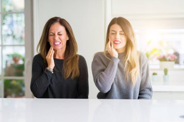 Anne ve kız güzel aile birlikte evde diş ağrısı ya da diş hastalıkları nedeniyle ağrılı ifade ile el ağız dokunmadan. Dişçi konsepti.