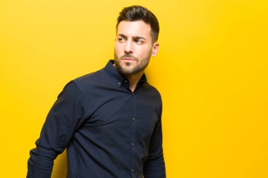 Genç yakışıklı adam possing ve modelleme sarı izole bac üzerinde