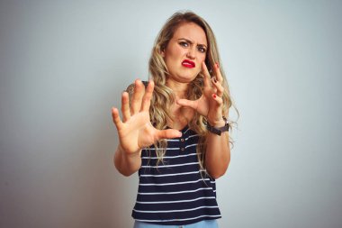 Beyaz izole arka plan üzerinde ayakta çizgili t-shirt giyen genç güzel kadın korkuyor ve el ile korku ifadesi stop jest ile dehşete, şok bağırıyor. Panik konsepti.