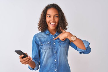 Genç Brezilyalı kadın kendini şaşırtıcı yüz işaret parmağı ile izole beyaz arka plan üzerinde ayakta Smartphone kullanarak