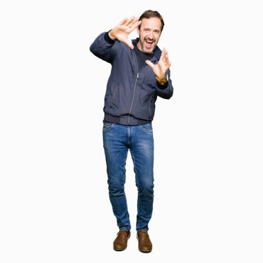 Orta yaş yakışıklı adam bir ceket giymiş el avuç içi ve parmaklar, kamera perspektifi kullanarak çerçeve yapıyor gülümseyen