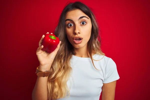 Ung Vacker Kvinna Som Håller Peppar Över Röd Isolerad Bakgrund — Stockfoto