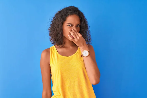 Jovem Brasileira Vestindo Camiseta Amarela Sobre Fundo Azul Isolado Cheirando — Fotografia de Stock