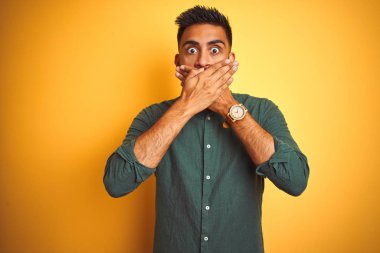 Genç Hint işadamı izole beyaz arka plan üzerinde ayakta zarif gömlek giyen hata için eller ile ağız kapsayan şok. Gizli konsept.