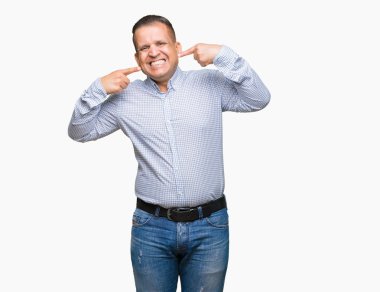 Orta yaş Arap iş adamı kendine güvenen gösterilen ve işaret parmakları diş ve ağız ile gülümseyen izole arka plan üzerinde. Sağlık kavramı.