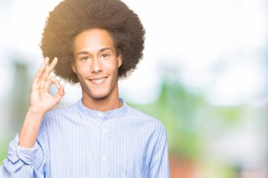 Afro saç gülümseyen genç Afro-Amerikan adam el ve parmaklar ok işaretiyle yapıyor olumlu. Başarılı ifade.