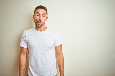 İzole arka plan yapma balık yüzüne dudaklı, çılgın ve komik bir jest Casual beyaz t-shirt giyen genç yakışıklı adam. Komik ifade.