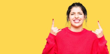 Kırmızı kazak ve rock simge elle yapıyor deli ifade ile bağırarak topuz giyen genç güzel kadın. Müzik yıldızı. Ağır kavramı.