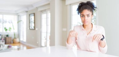 Afro saç ile güzel Afrikalı Amerikan kadın geniş açı üzgün ve üzgün görünümlü aşağı Işaret, parmaklarla yönü gösteren, mutsuz ve depresif.