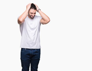 Genç adam giyiyor rahat beyaz t-shirt çünkü umutsuz ve stresli baş ağrısı acı izole arka plan üzerinde ağrı ve migren. Ellerini kafasına.