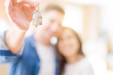 Güzel genç çift aşık ve yeni ev, yeni bir daireye hareket mutlu gülümseyen anahtarları gösteren sarılma