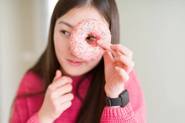 美丽的亚洲女人吃粉红糖甜甜圈认真面对思考问题 很困惑的想法 — 图库照片