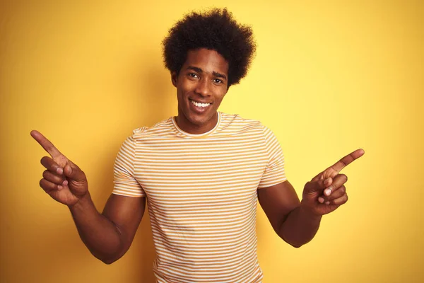 一个头发发满条纹的美国男子站在孤立的黄色背景上 自信地用手指指着不同的方向 广告的复制空间 — 图库照片
