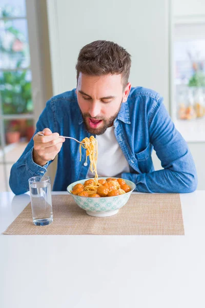 Schöner Mann isst Pasta mit Frikadellen und Tomatensauce bei hom — Stockfoto