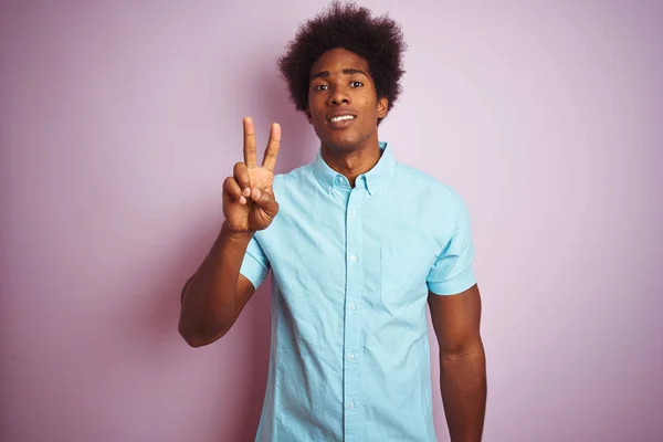 年轻的美国男子与非洲头发穿着蓝色衬衫站在孤立的粉红色背景显示和指向手指二号 同时微笑自信和快乐 — 图库照片