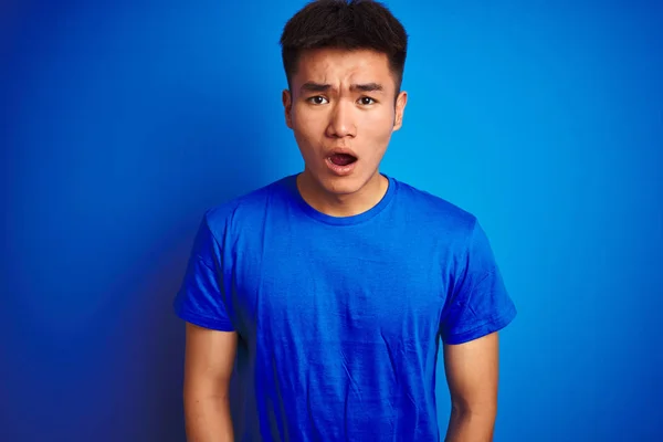 孤立した青い背景の上に立つTシャツを着た若いアジア人の男性は 驚きの表情 恐怖と興奮した顔でショックを受けました — ストック写真