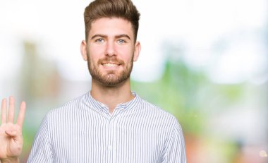 Genç yakışıklı adam kendini beğenmiş ve mutlu bir şekilde gülümserken dört numarayı işaret ediyor..