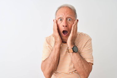 Üst düzey gri saçlı adam izole beyaz arka plan üzerinde duran çizgili t-shirt giyen korkmuş ve şok, sürpriz ve yüzünde elleri ile şaşırtıcı ifade