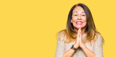 Moda kazak ellerle birlikte emin gülümseyen bağışlanmak için dua giyen güzel orta yaş kadın.