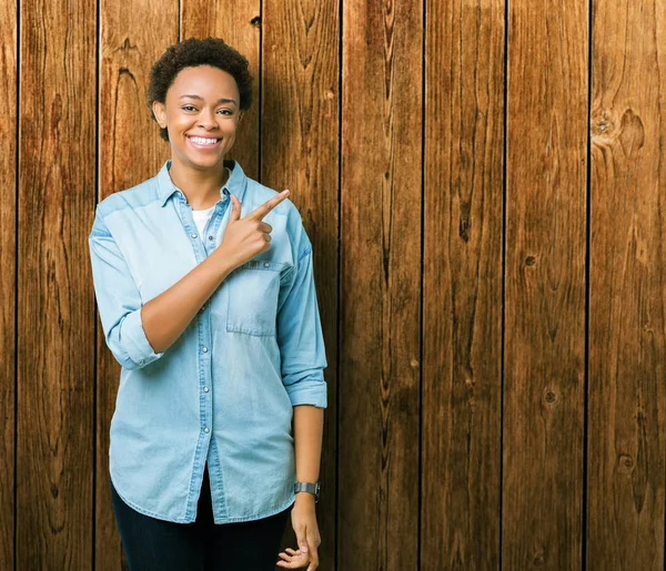 İzole arka neşeli bir gülümseme ile el ve parmak kadar yan yüzünde mutlu ve doğal ifade ile işaret yüz genç güzel Afrikalı-Amerikalı kadın