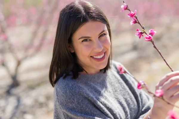 Schöne junge Frau lächelt fröhlich auf einem Pfirsichgarten mit pi — Stockfoto