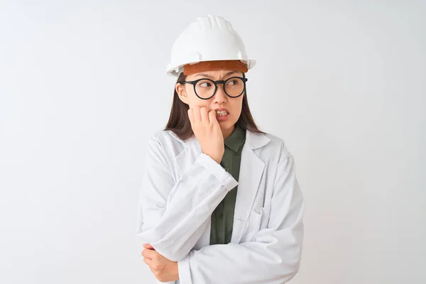 年轻的中国工程师妇女戴着外套头盔眼镜在孤立的白色背景看起来紧张和紧张 双手咬着指甲 焦虑问题 — 图库照片
