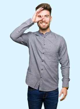 Genç yakışıklı iş casual adam gülümsüyor, parmakları ile mutlu yüz üzerinden seyir göz el ile ok jest yapıyor.